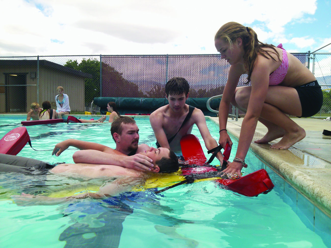 Lifeguards Robert and William Moore, assisted by Jessianne Joiner, remove Eddy Ivy from the pool during a neck and back rescue as part of their lifeguard training. Photos courtesy: Charles James.