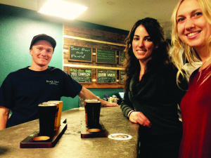 Black Doubt Brewery owner Drew Wallace serves Betty Hylton and Jessie Melton a flight of Black Doubt’s original beers. Photo courtesy: Rea.